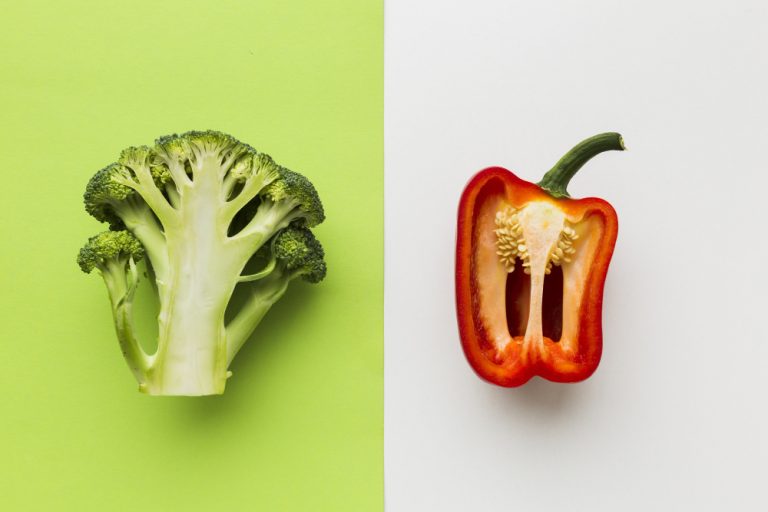 Heirloom vs. hybrid: half a head of broccoli on a green background beside a halved red pepper on white.